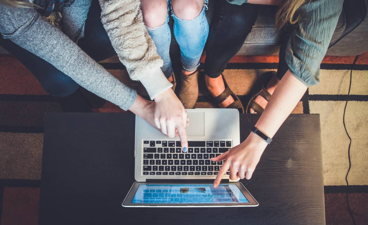 People collaborating and pointing at a laptop screen.