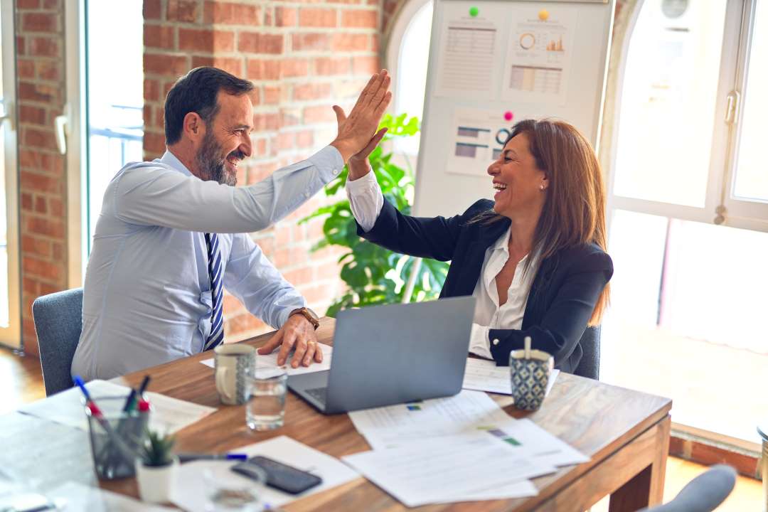 Colleagues celebrating with a high-five in office.