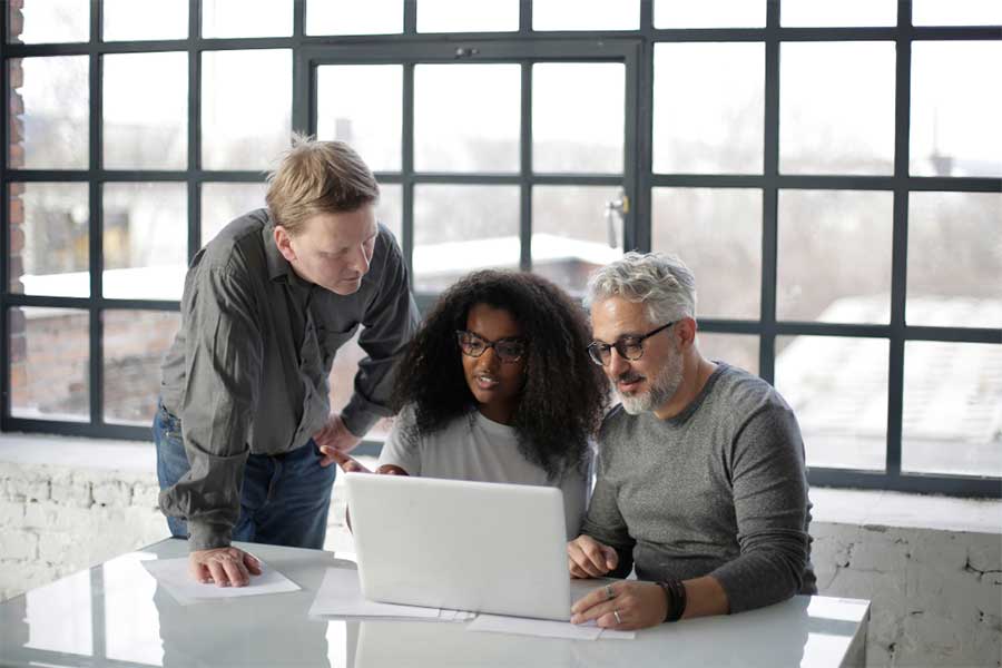 Three colleagues collaborating on a laptop in office.