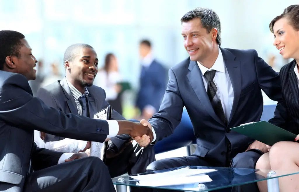 Business meeting with four people shaking hands.