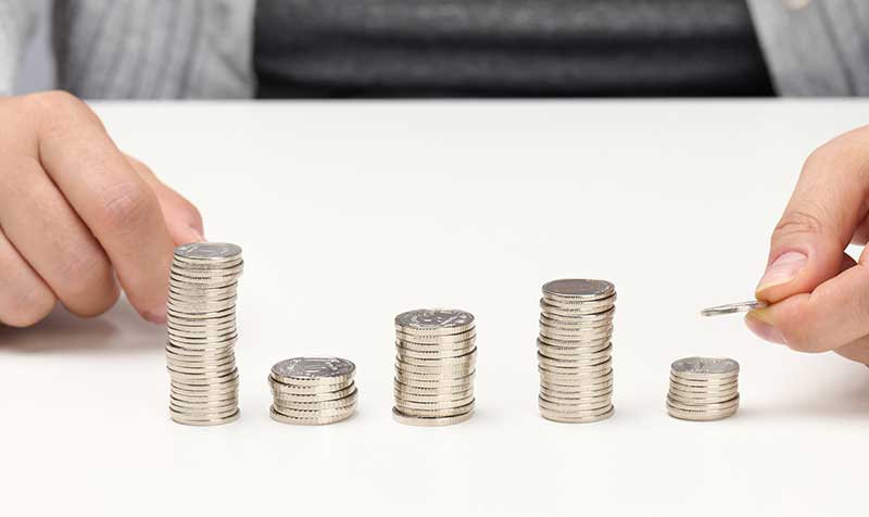 Hands organising stacks of coins on table.