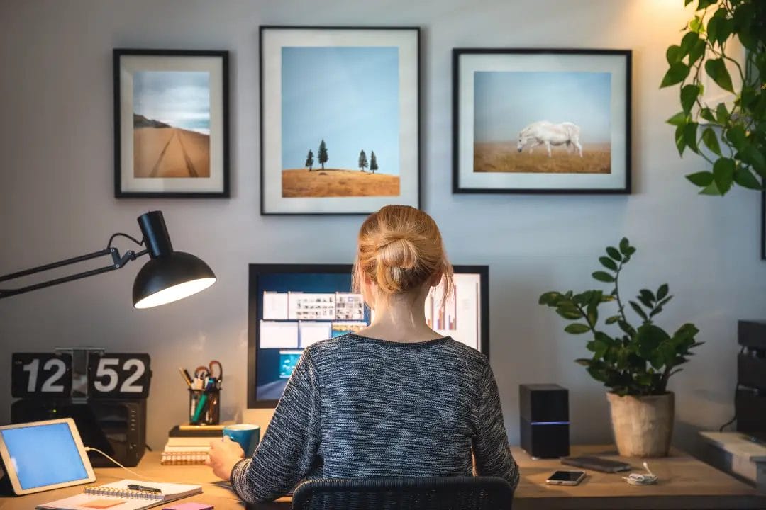 Person working at home office desk with art.