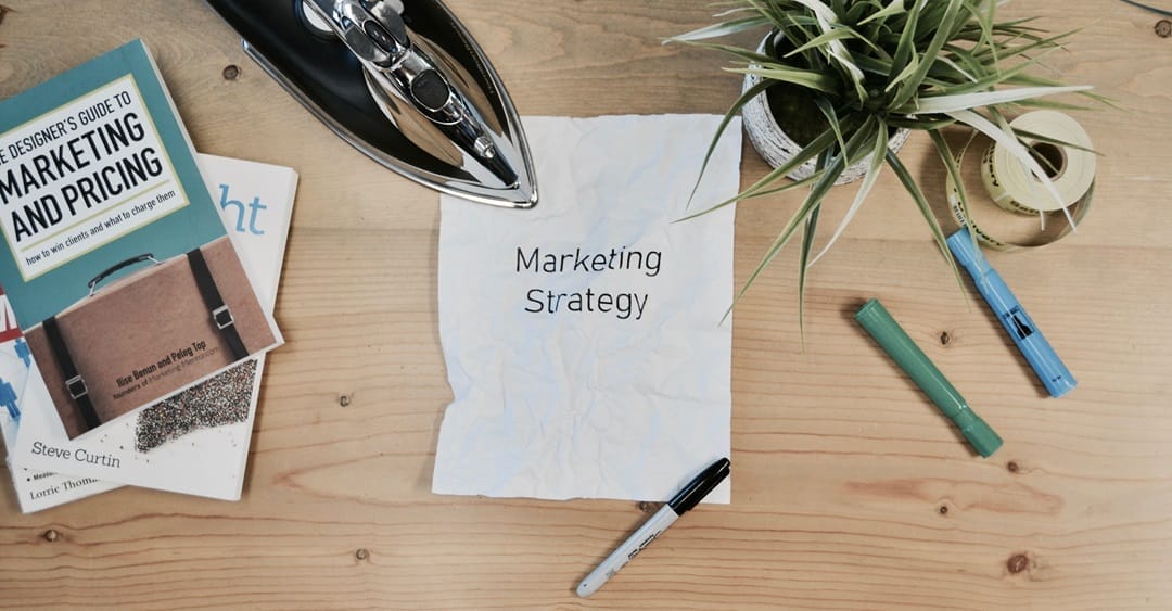 Marketing strategy plan on desk with books and tools.