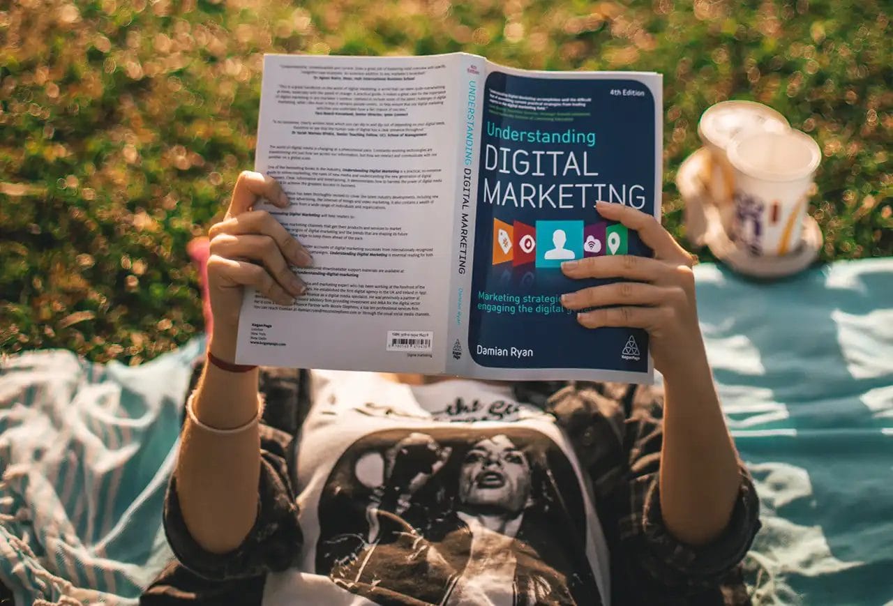 Person reads digital marketing book outdoors.