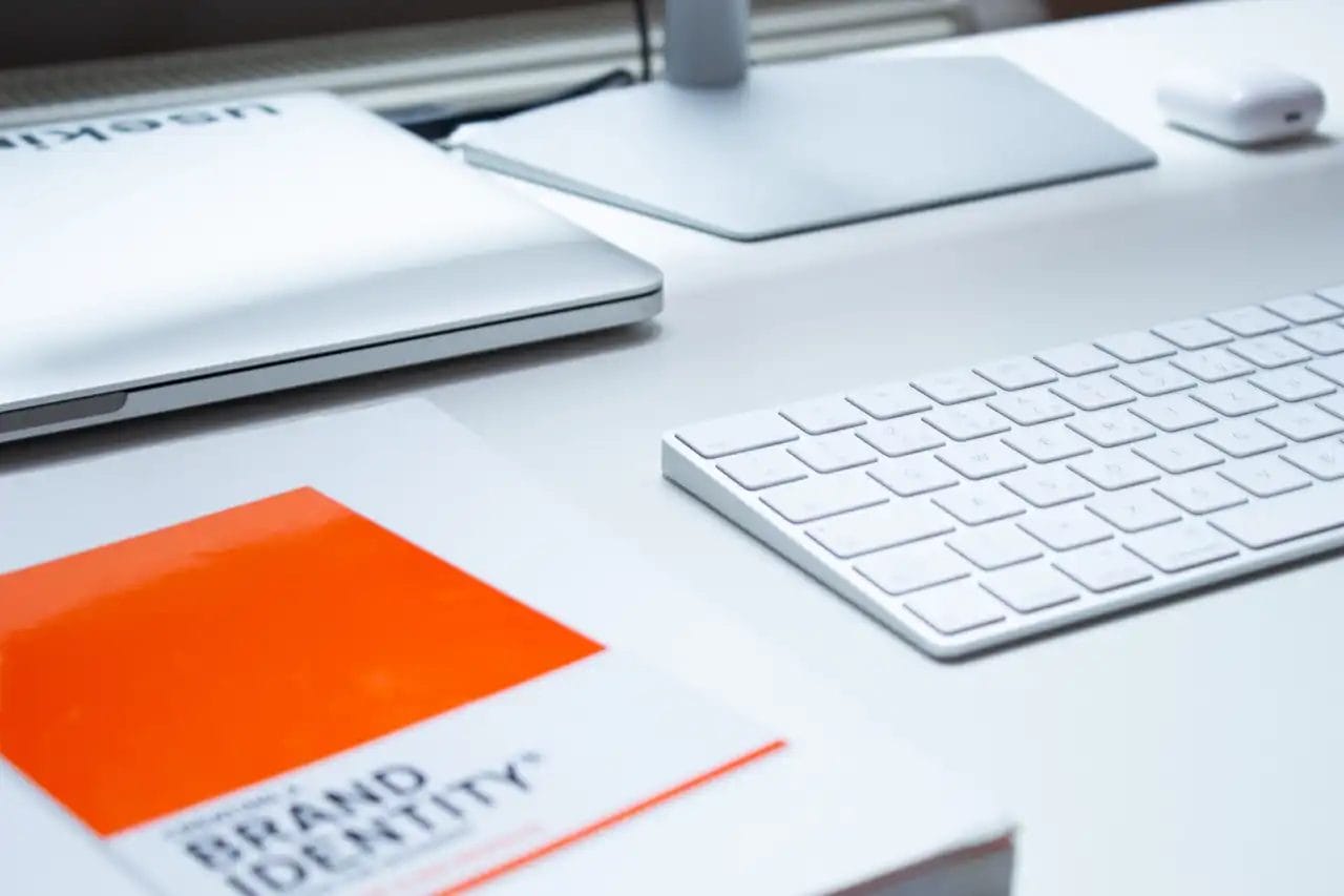 Desk with keyboard, laptop, brand identity booklet