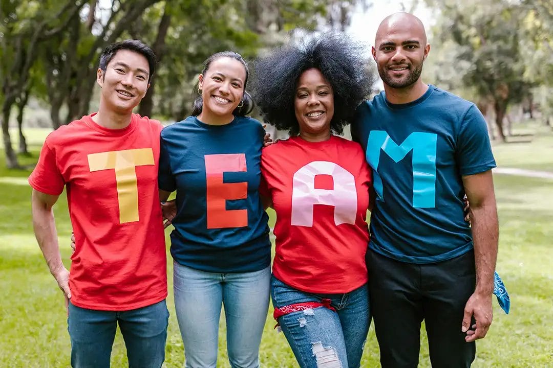 Diverse group wearing TEAM shirts outdoors.