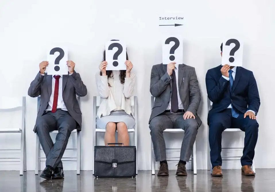 Candidates awaiting job interview holding question marks.