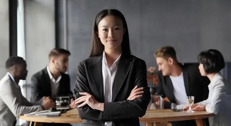 Confident businesswoman stands in front of meeting colleagues.