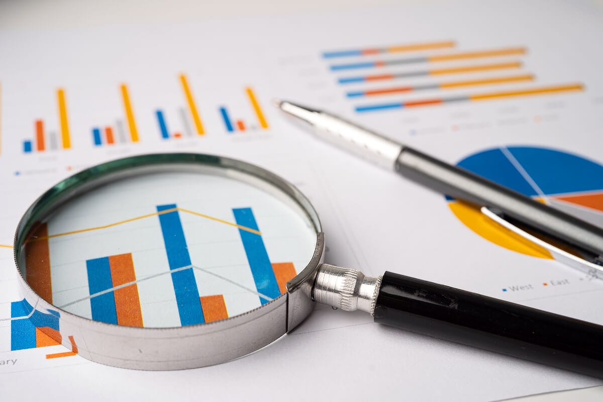 Magnifying glass analyzing business charts and graphs.