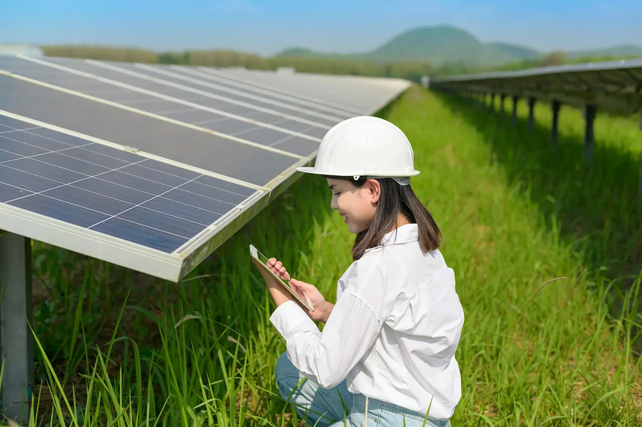 Engineer inspecting solar panels with tablet on site.