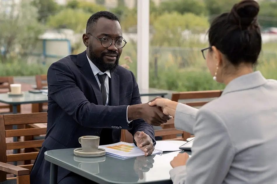 Business meeting handshake over coffee outside.