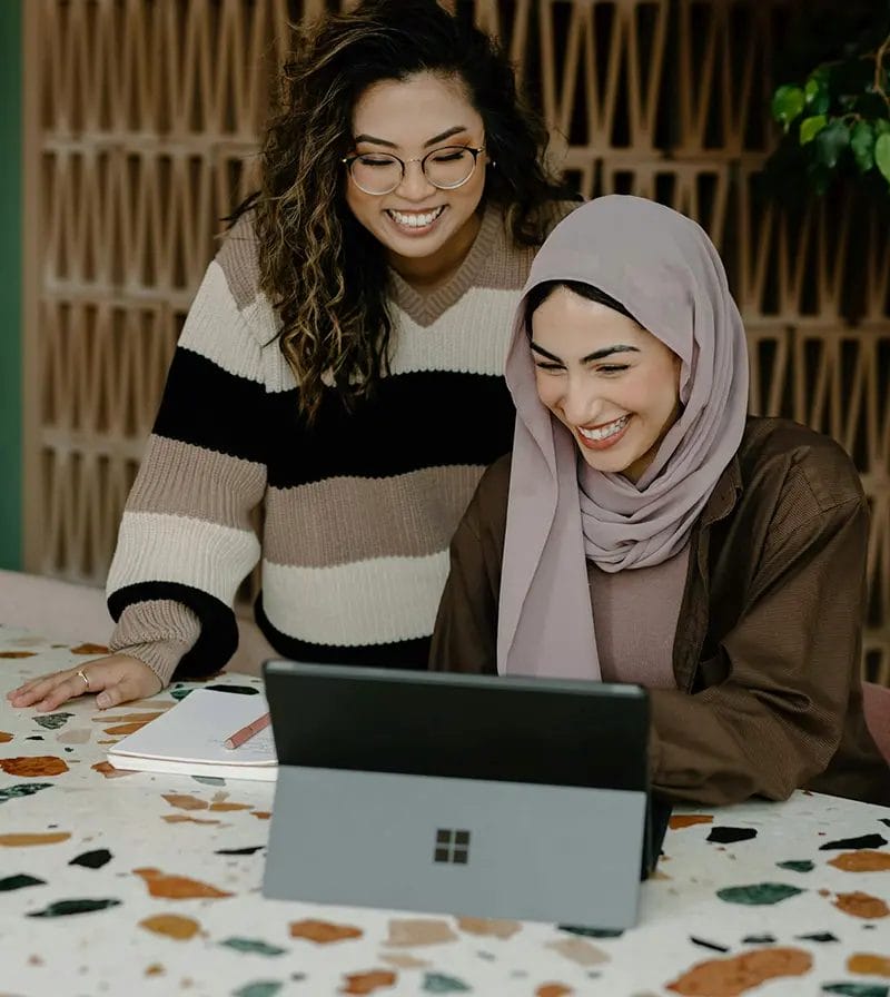 Two women smiling at a laptop together.