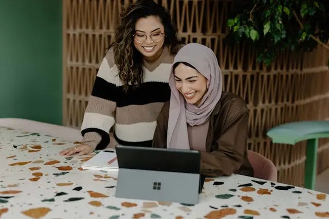 Two women smiling at a laptop together.