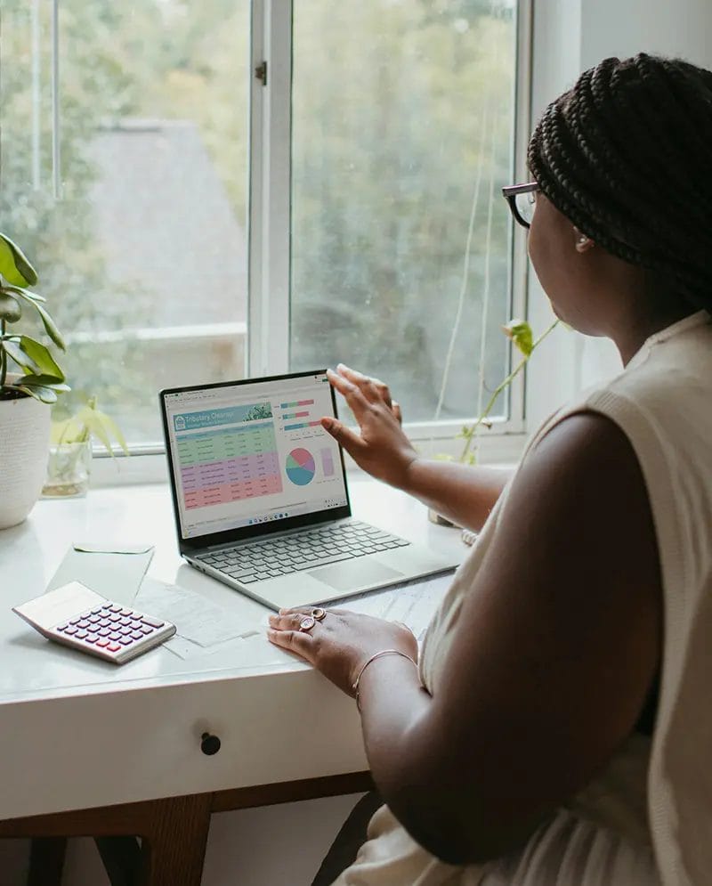 Woman working on laptop with financial charts.