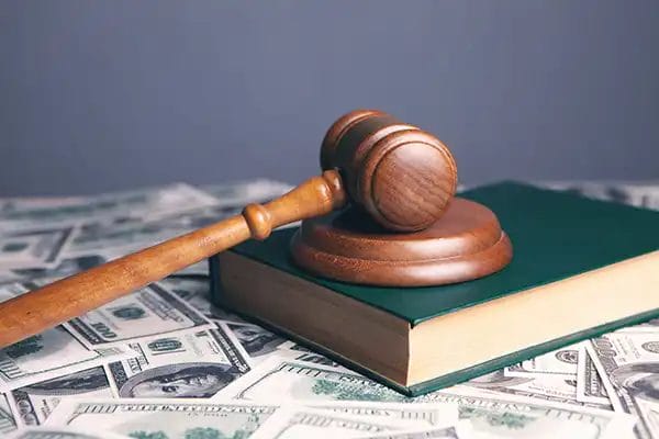 Wooden gavel on book and dollar notes.