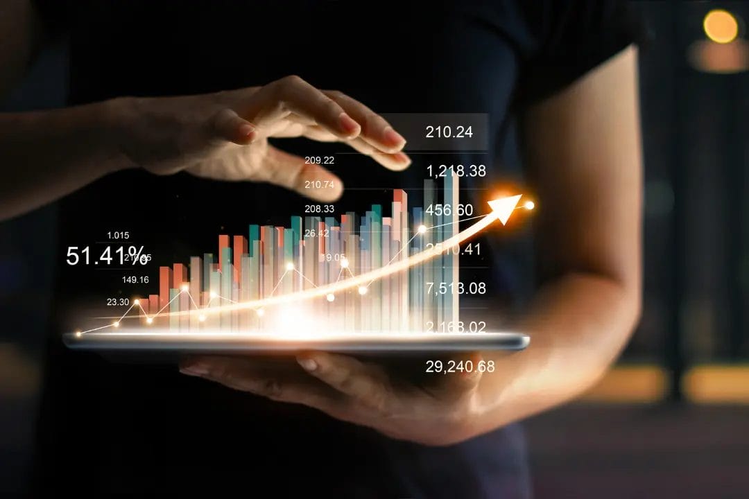 Hands holding tablet with rising graph.