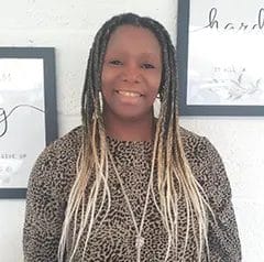 Smiling person with braided hair, leopard print top.