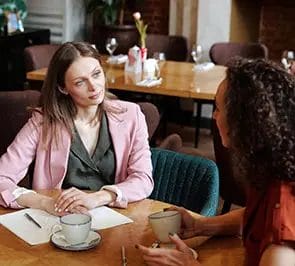 Two women talking in a restaurant over coffee.