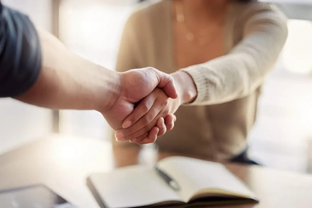 Close-up handshake over open notebook.